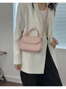 Détail d'un sac bandoulière rose en cuir texturé avec des accents métalliques dorés