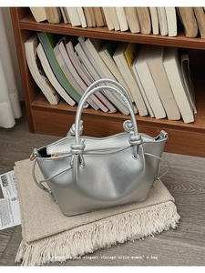 Detailed view of silver metallic bucket bag featuring unique knotted handles on a cozy rug