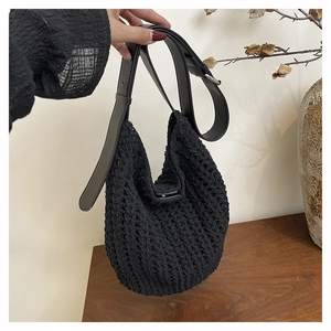 Detail of black knit tote bag showing 3D woven texture and adjustable leather shoulder strap