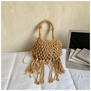 Detail of bohemian woven straw bag featuring pearl handle and decorative fringe accents