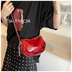 Close-up of vibrant red patent leather crossbody bag with chain strap and metal logo