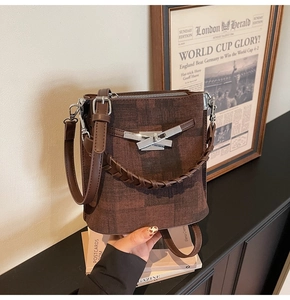 Detail of vintage brown bucket bag with silver clasp, leather trim and woven handle