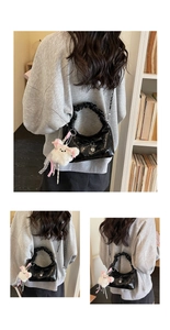 Détail du sac à main noir brillant avec poignée froncée et pendentif ours blanc
