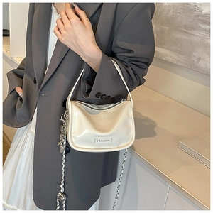 Close-up of creamy white glossy leather handbag featuring silver chain and fashion tag