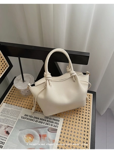 Detail of creamy white vintage tote bag with knot handle and decorative side drawstring