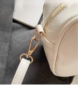 Detailed close-up of premium light gold metal hooks and white leather stitching on bag