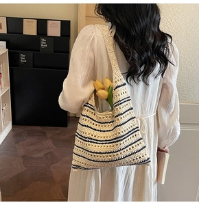 Detail of a large woven straw bucket bag showing striped knit pattern and wide strap