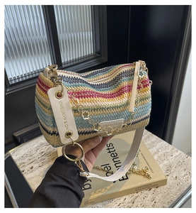Detailed view of colorful striped woven baguette bag with gold chain and branded strap