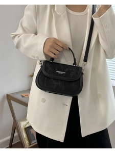 Détail du sac à bandoulière noir avec logo blanc et poignée supérieure texturée