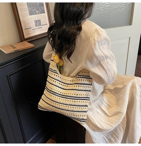 Detail of striped crochet tote bag in beige and navy, showing the soft woven knit texture