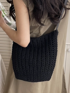 Minimalist black woven crochet tote bag with leather strap shown in a lifestyle setting