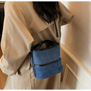 Details der blauen Denim-Beuteltasche mit schwarzen Lederbesätzen und Zylinderform