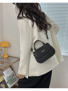 Détail du petit sac à bandoulière noir en cuir texturé avec une sangle réglable