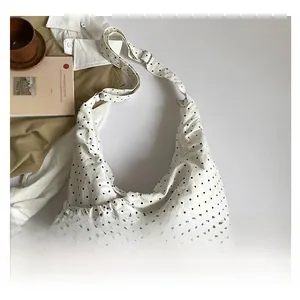 Detailed macro view of white canvas hobo bag with black polka dots and side drawstring