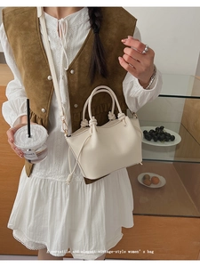 Close-up of cream white retro handbag with decorative knots and a slim shoulder strap