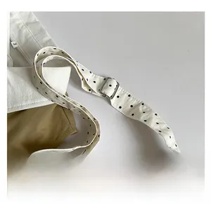 Detail of adjustable canvas shoulder strap with black polka dots and silver metal buckle