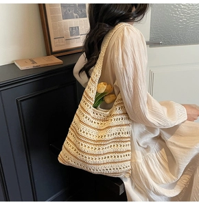 Close-up of hollow straw shoulder bag with stripes and elegant yellow tulips inside