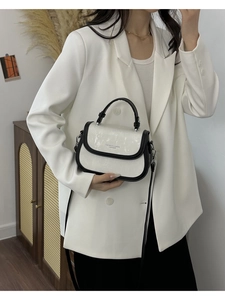 Détail du petit sac blanc porté en bandoulière par un mannequin dans un intérieur élégant