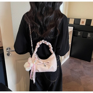 Détail du sac rose avec nœud, poignée plissée et breloque cœur porté par un modèle