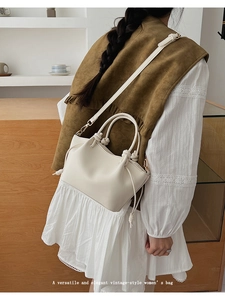 Close-up of minimalist cream-white shoulder bag featuring elegant knotted handle details