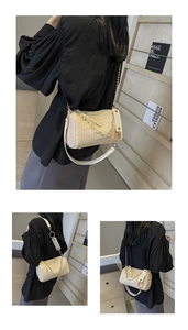 Detailed close-up of woven beige straw cylinder bag with golden chain and wide shoulder strap