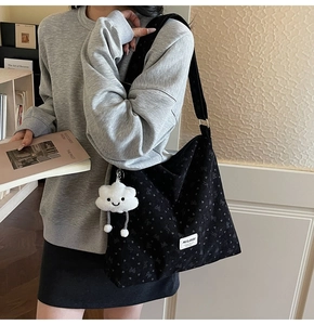 Detail of black corduroy tote bag with heart patterns and plush cloud charm