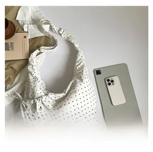 Flat lay of large polka dot canvas hobo bag with iPad and lifestyle accessories