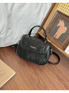 Détail du petit sac carré noir texturé avec poignée et finitions métalliques élégantes