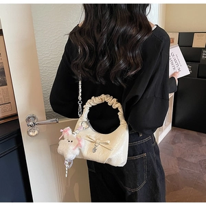 Détail d'un sac plissé crème avec une peluche de lapin mignonne et un pendentif coeur