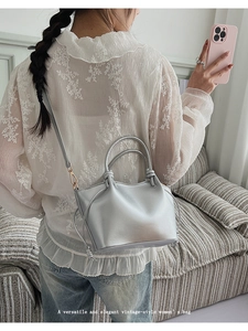 Silver metallic bucket bag with round handles worn with a lace blouse for a vintage look