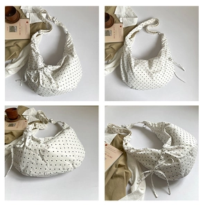Detailed view of white polka dot canvas messenger bag with adjustable strap and side bows