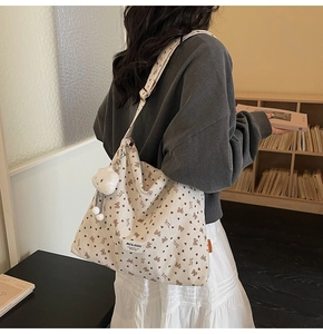 Detail of corduroy tote bag featuring bear print and plush cloud charm accessory
