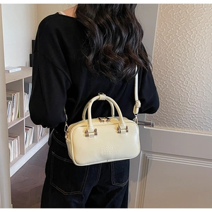 Rear view of a model carrying a cream yellow Boston bag in a minimalist home interior