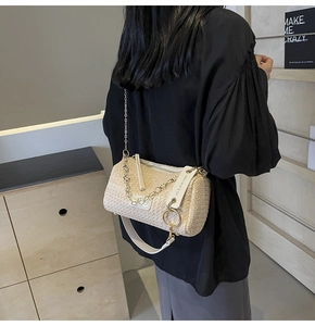 Detail of beige woven cylinder pillow bag with stylish white leather strap and gold chain link