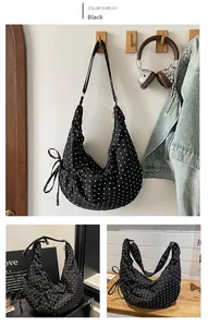 Detail view of large black Hobo bag with white polka dots and drawstring bow accessory