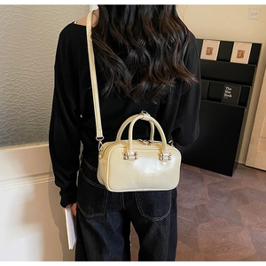 Close-up of cream white handbag featuring embossed logo and metallic stud detailing