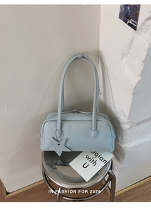 Détail du sac baguette en similicuir bleu clair avec breloque étoile sur tabouret