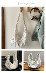 Detail of white polka dot canvas shoulder bag showing drawstring pleats and large capacity
