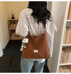 Brown corduroy tote bag detail with floral bow patterns and a white cloud plush charm