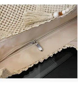Detailed close-up of woven tote bag with smooth zipper closure and white tassel charm