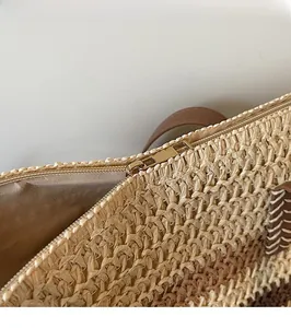 Close-up of golden zipper detail on rainbow striped straw woven beach tote bag