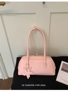 Détail du sac baguette rose clair avec pendentif étoile et fermeture éclair sur coussin
