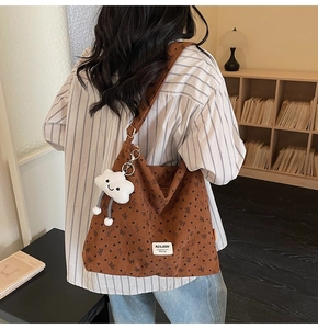 Detail of brown corduroy tote bag with black butterfly prints and a plush cloud charm