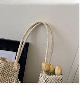 Detail of sturdy braided rope handles and hollow mesh texture on a beige woven tote bag