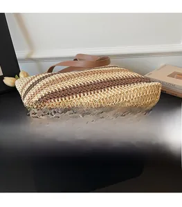 Vue détaillée du sac cabas en paille tressée montrant la texture rayée et la base solide
