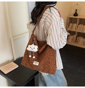 Detail of brown corduroy tote bag with heart patterns and white cloud plush charm