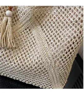 Close-up of beige hollow-out woven tote bag with fringe tassels and wooden beads detail