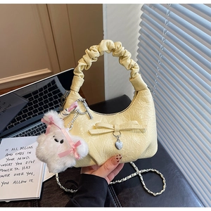 Détail d'un sac nuage plissé jaune crème avec nœud, breloque cœur et pendentif lapin