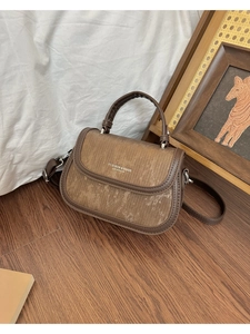 Détail de la texture cuir marron et tissu rayé sur ce petit sac carré en bandoulière