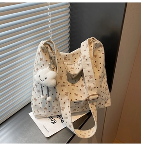 Detail of cream corduroy tote bag with brown bows, golden buckle and cloud charm